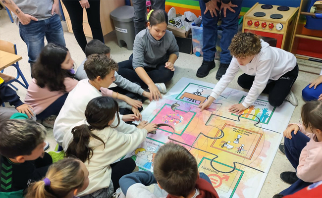 Un grupo de niños sentados en el suelo haciendo un puzle gigante