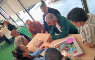Un grupo de personas mayores sentados alrededor de una mesa jugando a juegos de mesa