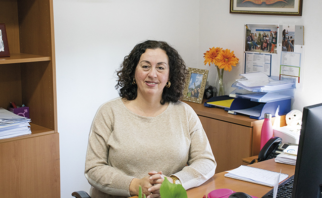 Trabajadora de la asociación sentada en su oficina, rodeada de documentos y elementos decorativos. La imagen refleja el trabajo y compromiso en la gestión y apoyo a personas con discapacidad intelectual en Sevilla y menores del sistema de protección.